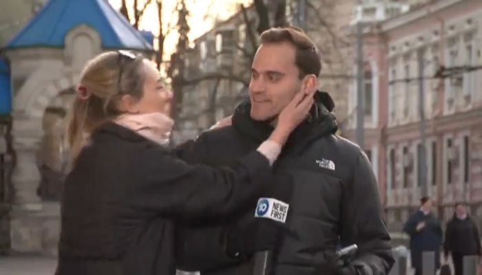 The presenter reacts dramatically, as a blonde bystander rushes up to him and kisses him on the cheek.— Screengrab via Twitter/@JohnpaulGonzo