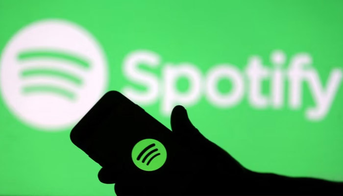 A smartphone is seen in front of a screen projection of the Spotify logo in this picture illustration taken April 1, 2018. — Reuters