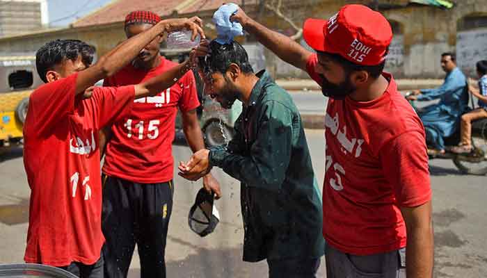 Volunteers of the Edhi Foundation cool down a man with water during a hot day in Karachi on April 11, 2021. — AFP