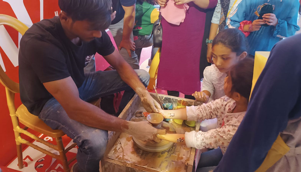 A person helps a child make a pot on the potters wheel during the Food Festival. — By the author