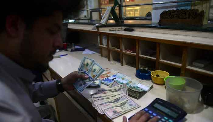 A dealer holds US dollars at a money exchange market in Karachi on January 26, 2023. — AFP