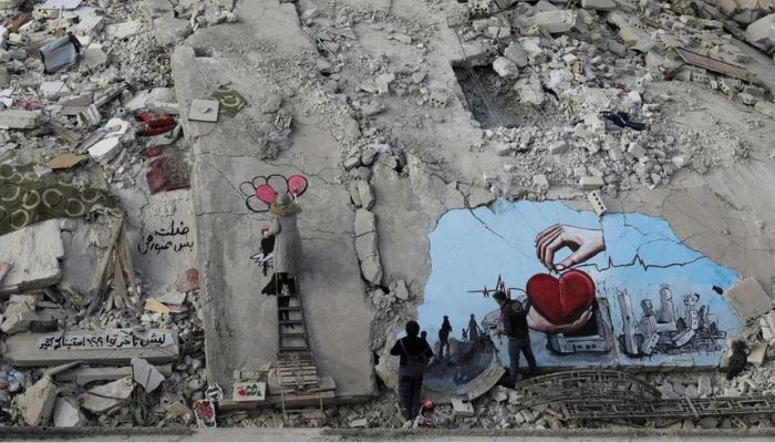 Syrian artists Aziz Asmar and Salam Hamed paint street art on the rubble of damaged buildings in the aftermath of a deadly earthquake, in the rebel-held town of Jandaris, Syria February 22, 2023.— Reuters