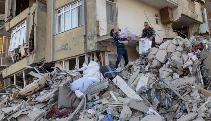 Arsin and his father take belongings out of their destroyed apartment in the aftermath of the deadly earthquake in Antakya, Hatay province, Turkey, February 20, 2023. — Reuters