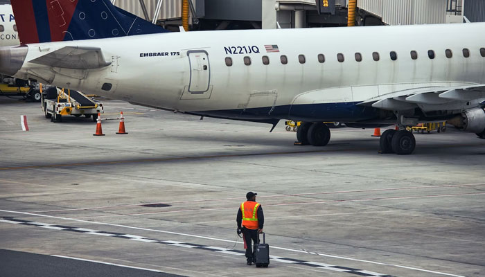 A worker walks with luggage to the airplane at the LaGuardia Airport, Queens, NY, USA. Representational image from Unsplash