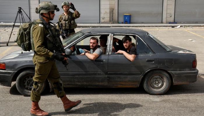 Israeli settlers sit in a car next to Israeli members of the military, in the aftermath of an incident where a Palestinian gunman killed two Israeli settlers, near Hawara in the Israeli-occupied West Bank, February 27, 2023.— Reuters