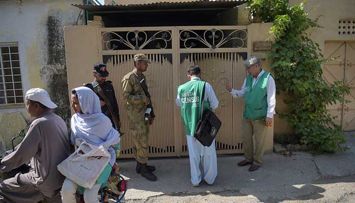 Officials from the Pakistan Bureau of Statistics collect information from a resident as soldiers stand guard during the second phase of the national census in Islamabad, April 25, 2017. — AFP