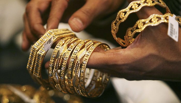 An undated image of a jewellery shopkeeper showing gold bangles to a customer. — Reuters/File
