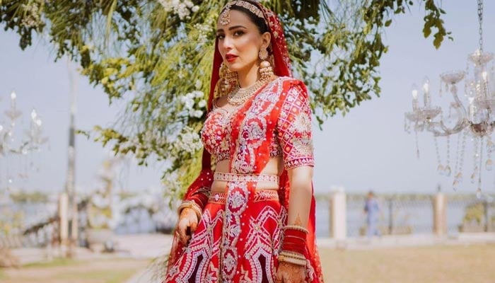 Pakistani actress Ushna Shah poses for the camera on her wedding day in a bright red lehnga. — Instagram/@wardhasaleemofficial