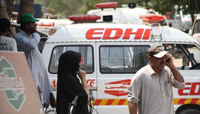 Photo of a man speaking on a call with the Edhi Foundations ambulance parked behind him. — Reuters/File