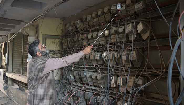 A Pakistani employee of the state-run Islamabad Electric Supply Company (IESCO), takes a meter reading with his smartphone at a commercial building in Islamabad. — AFP