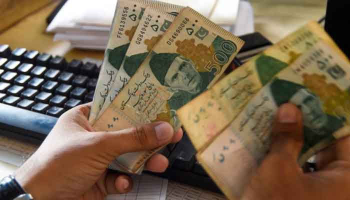 Money trader counts rupee notes at an exchange shop. — AFP/File