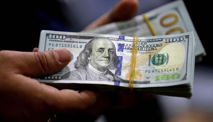 An undated image of a currency dealer holding a stack of $100 notes. — AFP/File