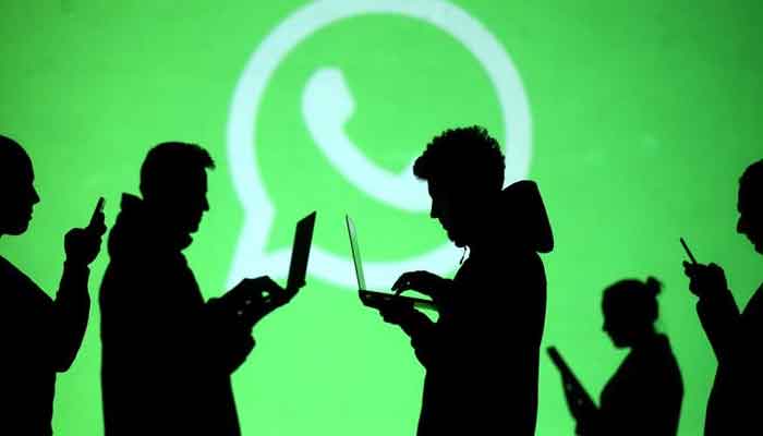 Silhouettes of laptop and mobile device users are seen next to a screen projection of Whatsapp logo in this picture illustration taken March 28, 2018. — Reuters