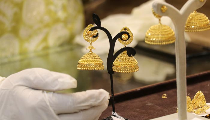 An undated image of a goldsmith showing gold earrings to a customer. — Reuters/File