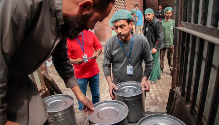 A worker at the Pakistani charity Saylani supervises the loading of vats of freshly cooked food into an open-backed jeep in the city of Faisalabad. — NPR