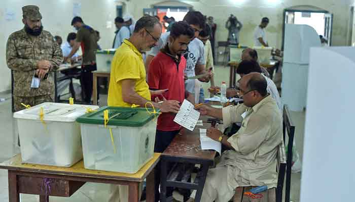 Pakistani men line up as election officials check their ballot papers during voting in Pakistans general election at a polling station in Lahore, Pakistan, on July 25, 2018. — AFP