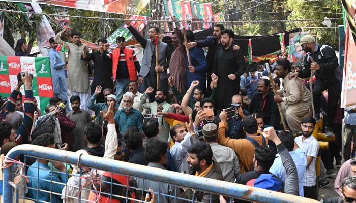 Supporters of Imran Khan chant slogans outside his Zaman Park residence in Lahore on March 5, 2023. — AFP