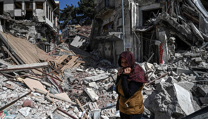 A woman stands among the rubble of collapsed buildings in Hatay on March 6, 2023, one month after a massive earthquake struck southeastern Turkey. A massive 7.8-magnitude earthquake rocked huge swathes of Turkey and parts of Syria on February 6, 2023. —AFP