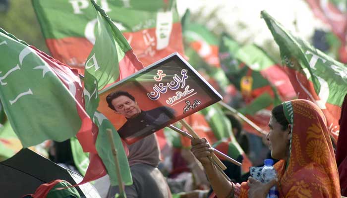 Supporters of PTI hold party flags during a public gathering (jalsa) at Parade Ground, in Islamabad. — Online