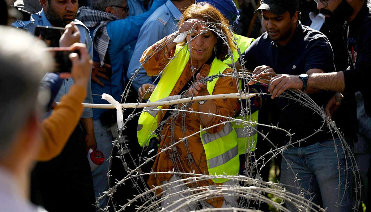 An activist of Aurat March removes barbed wires as police try to stop them during a rally in Islamabad. — AFP