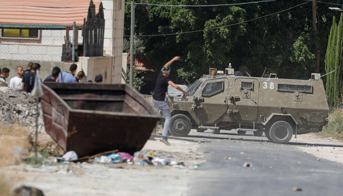 A Palestinian hurls a stone at an Israeli army vehicle during clashes after Israeli forces killed Palestinian gunmen in a raid, in Jenin in the Israeli-occupied West Bank. — Reuters/File