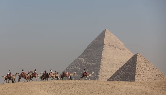 Tourists ride camels in front of the Great Pyramids plateau in Giza, Egypt December 11, 2022. — Reuters