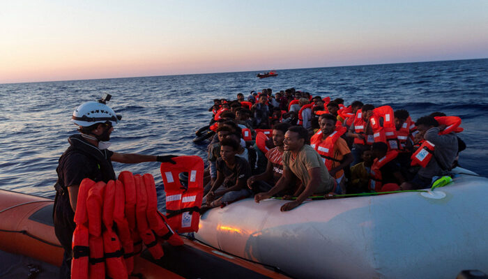 Crew member gives lifejackets to migrants on an overcrowded inflatable boat in the Mediterranean Sea, July 23, 2022.— Reuters.