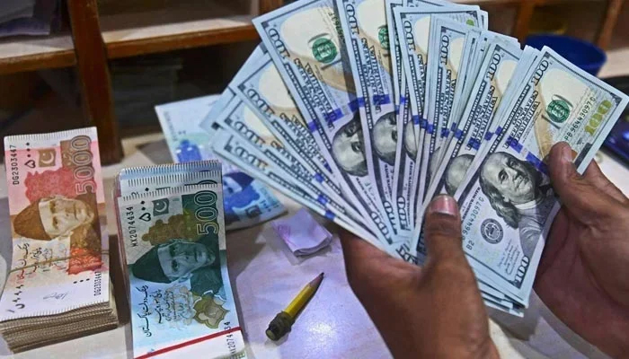 A currency dealer counts US dollars at a shop in Karachi. — AFP/File