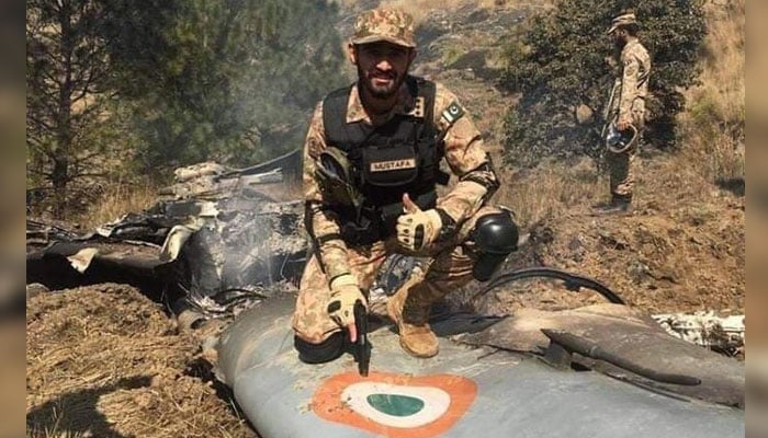 A Pakistan army soldier poses for a photo while sitting on the debris of an Indian fighter jet shot down by PAF. — Radio Pakistan/File