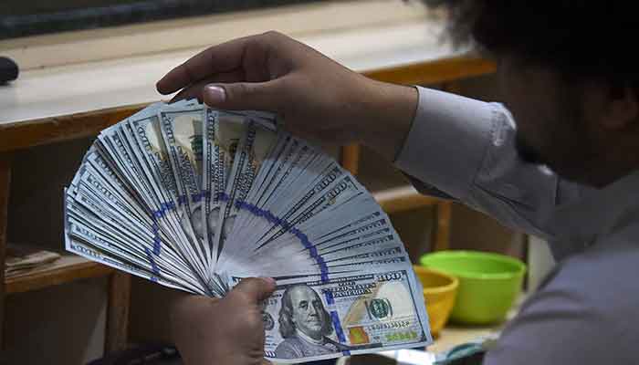 A dealer counts US dollars at a money exchange market in Karachi on January 26, 2023. — AFP