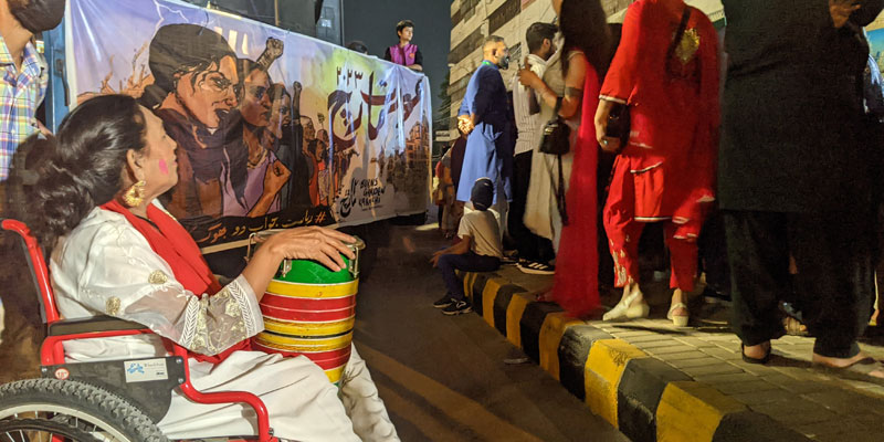 A differently-abled woman at the Aurat March 2023, sitting in her wheelchair with a dhol in her hand.— photo by author