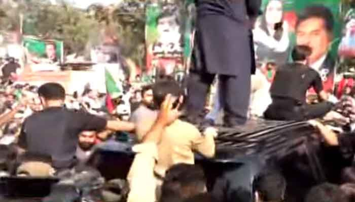 PTI workers alongside PTI Chairman Imran Khans vehicle at Zaman Park in Lahore, on March 13, 2023, in this still taken from a video. — Twitter/PTI