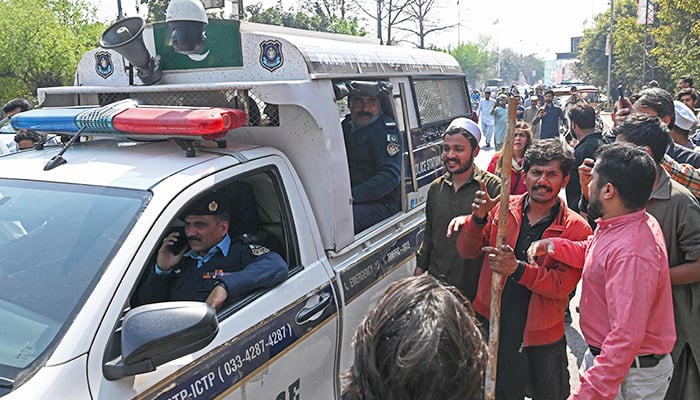 Supporters of former prime minister Imran Khan chant slogans outside his house in Lahore on March 5, 2023. — AFP