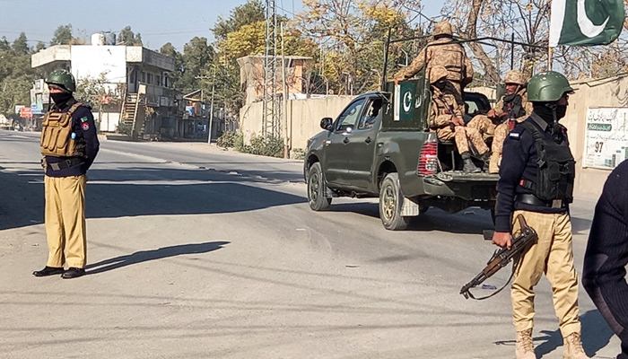 An Army vehicle patrols, past police officers stand guard along a road, near cantonment area in Bannu, on December 21, 2022. — Reuters