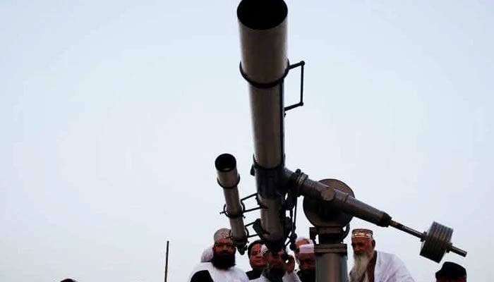 Members of the Ruet-e-Hilal Committee use a telescope to sight the moon. — Reuters/File