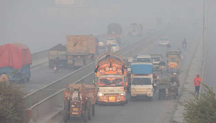 Vehicles move amid dense smog in Lahore on November 24, 2021. — Reuters