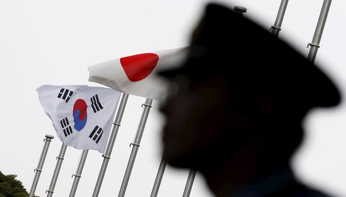 A police officer stands guard near Japan and South Korean national flags at a hotel, where South Korean embassy in Japan is holding the reception to mark the 50th anniversary of normalisation of ties between Seoul and Tokyo, in Tokyo June 22, 2015. — Reuters/File