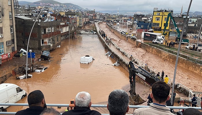 People stand at a high pont looking down at the flood waters in Sanliurfa, southeastern Turkey on March 15, 2023. — AFP