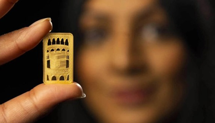 A woman holds the gold bar depicting the Kaaba. — UK Royal Mint