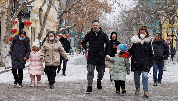 People walk with children in a pedestrian street in Harbin, Heilongjiang Province, China, February 10, 2023. — Reuters