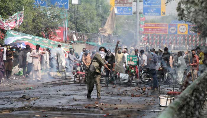 A supporter of PTI chief Imran Khan throws stones towards police during clashes in Lahore, Pakistan, March 15, 2023. — Reuters