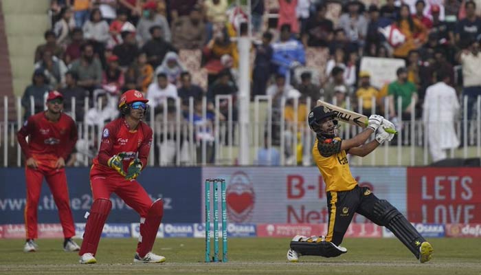 Peshawar Zalmi batter hits a shot while Islamabad United wicketkeeper looks on during the 29th fixture of the Pakistan Super League played at Pindi Cricket Stadium in Rawalpindi on March 12, 2023. — PSL
