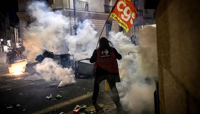 A Demonstrator holds a CGT flag during a demonstration after the French government pushed a pensions reform through parliament without a vote, using the article 49.3 of the constitution, in Nantes, western France, on March 16, 2023. AFP