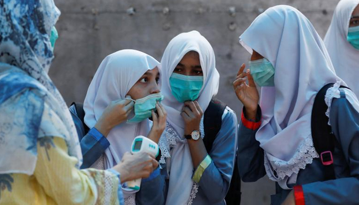 Students adjust their protective masks as they get their temperature checked before entering a class as schools reopen amid the coronavirus disease (COVID-19) pandemic. — Reuters/File