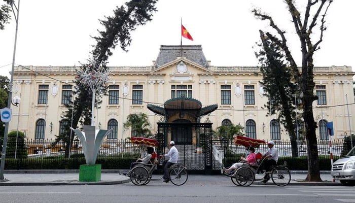 Men transport people on three-wheel cyclo past the Government Guesthouse in Hanoi, Vietnam. — Reuters/File