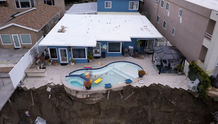 A backyard pool is left hanging on a cliff side after torrential rain brought havoc on the beachfront town of San Clemente, California, US on March 16, 2023. — Reuters