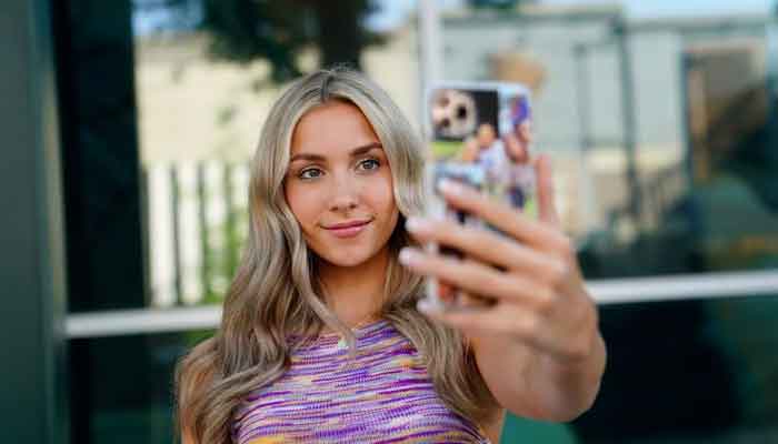 Katie Feeney, a social media personality, poses with her phone at a shopping center where she films many of her videos, in Gaithersburg, Maryland, U.S., May 25, 2021. — Reuters