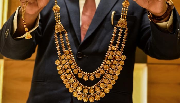 An undated image of a goldsmith showing a necklace to a customer. — AFP/File