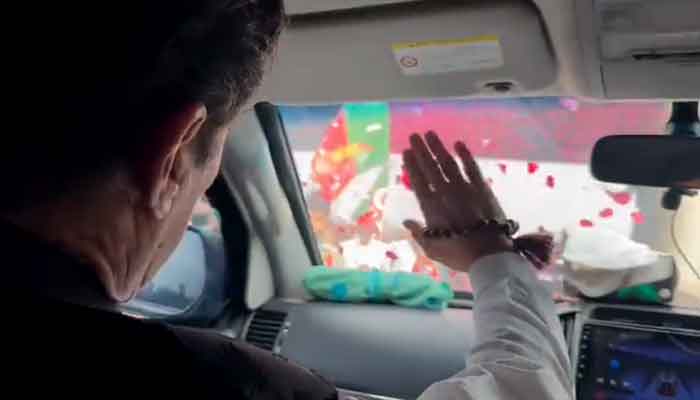 PTI chief Imran Khan waves to supporters on his way to Islamabad. —PTI/Twitter