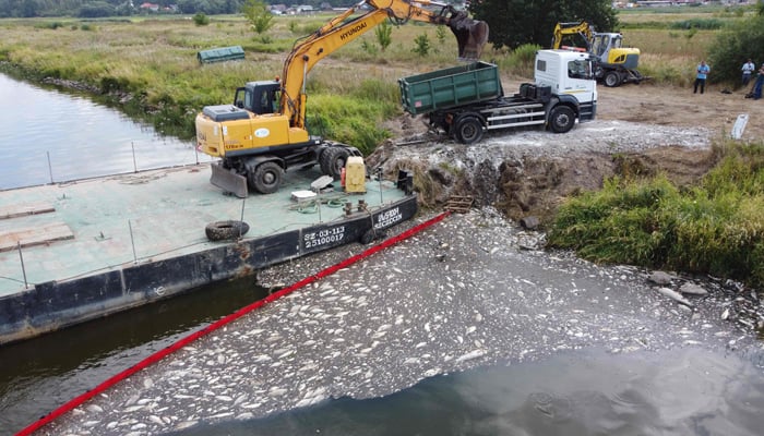An aerial picture taken on August 15, 2022 shows a floating damm used to encircle dead fish on the river Oder and an excavator to remove them in Krajnik Dolny, north-western Poland. — AFP